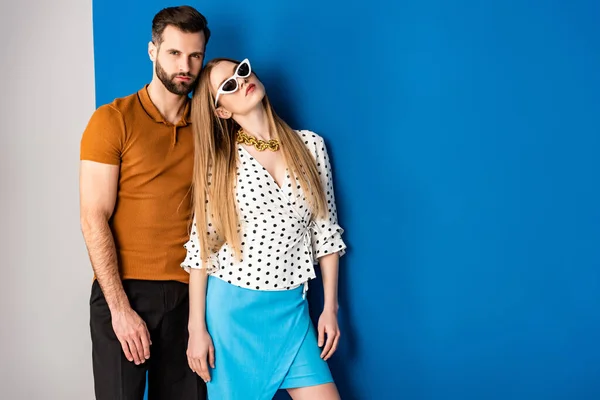 Beautiful couple posing in summer clothes and sunglasses on grey and blue — Stock Photo