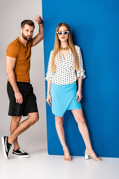 Beautiful couple posing in summer clothes and sunglasses on grey and blue — Stock Photo