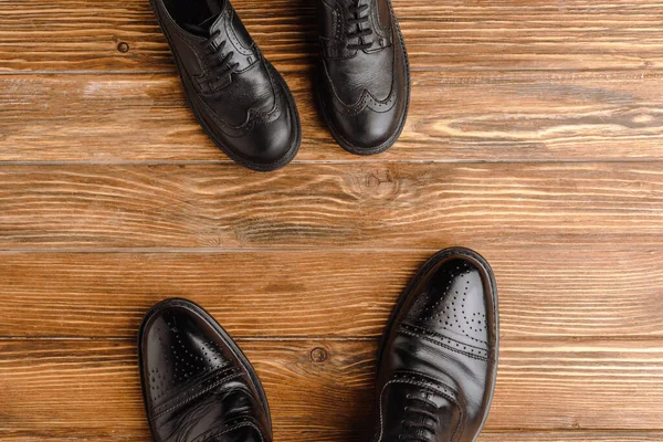 Top view of mens and childrens black classic shoes on wooden background, fathers day concept — Stock Photo