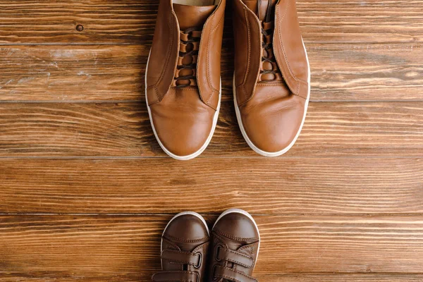 Vista superior de los hombres y los niños zapatos casuales beige sobre fondo de madera, el concepto de día de los padres - foto de stock