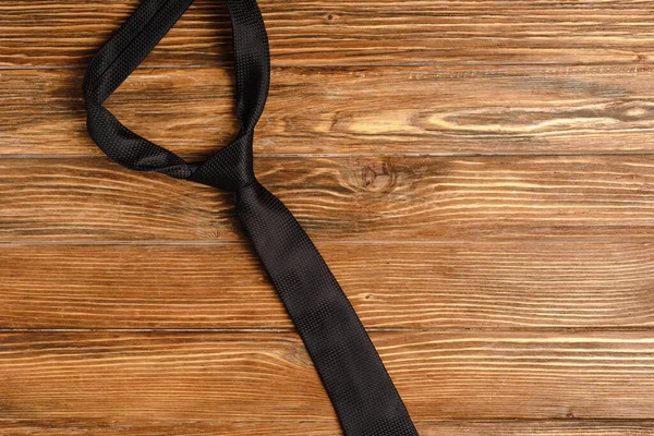Верхний вид мужской простой черный галстук на деревянном фоне — стоковое фото