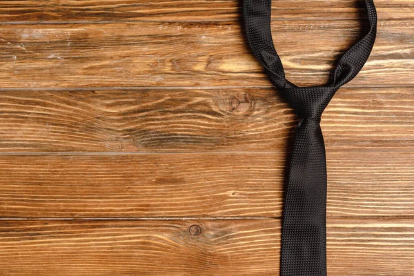 Верхний вид мужского черного галстука на деревянном фоне — стоковое фото