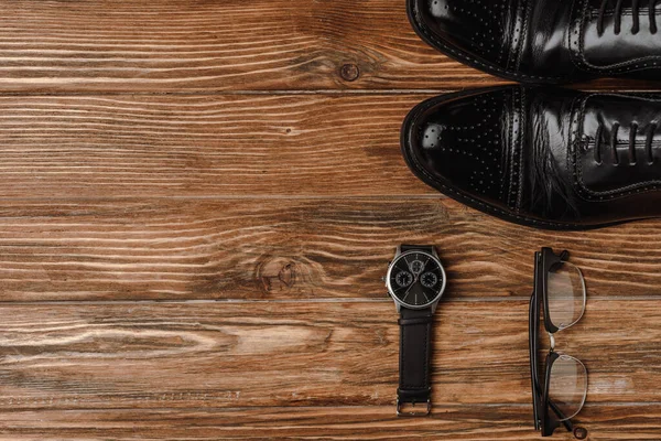 Top view of mens black classic shoes, wristwatch and glasses on wooden background — Stock Photo