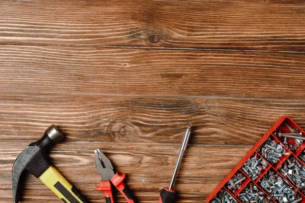 Vue de dessus des outils de réparation et des écrous et boulons sur fond en bois — Photo de stock