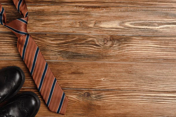 Draufsicht auf Herrenschuhe, elegante gestreifte Krawatte auf Holzhintergrund — Stockfoto