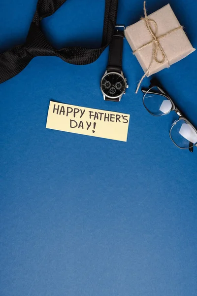 Top view of gift box, greeting card with lettering happy fathers day, mens accessories on blue background — Stock Photo