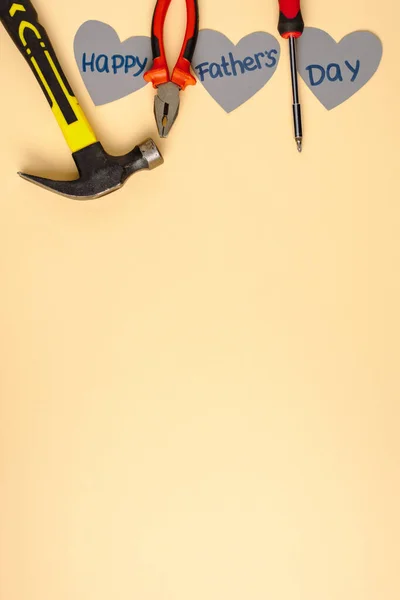 Top view of hammer, screwdriver, pliers and grey paper hearts with lettering happy fathers day on beige background — Stock Photo