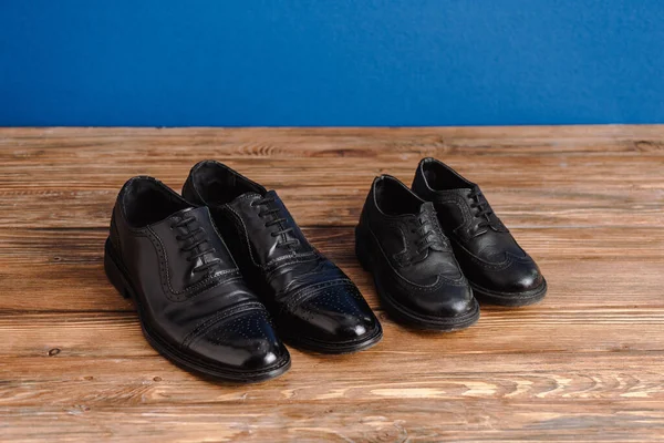 Vue grand angle des chaussures noires pour hommes et enfants isolées sur le bleu, concept de fête des pères — Photo de stock