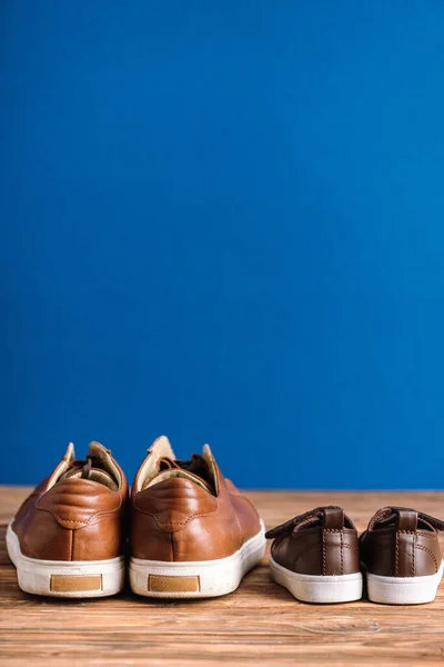 Mens and childrens casual beige shoes on wooden surface isolated on blue, fathers day concept — Stock Photo