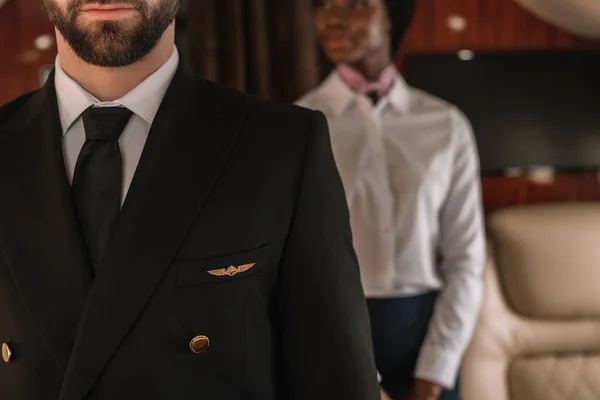 Ausgeschnittene Ansicht von Pilotin und afrikanisch-amerikanischer Stewardess im Privatflugzeug — Stockfoto