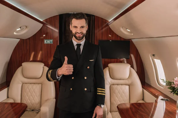 Красивый пилот частного самолета показывает большой палец вверх, улыбаясь в камеру — стоковое фото