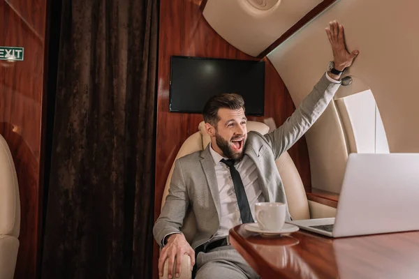 Excited businessman touching wall while sitting in private plane — Stock Photo