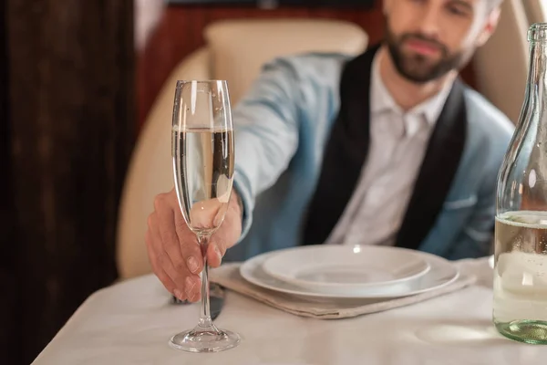Enfoque selectivo del hombre elegante tomando una copa de champán de la mesa servida en avión privado - foto de stock