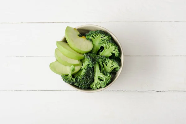 Vue de dessus de pomme verte fraîche et brocoli sur la surface en bois blanc — Photo de stock