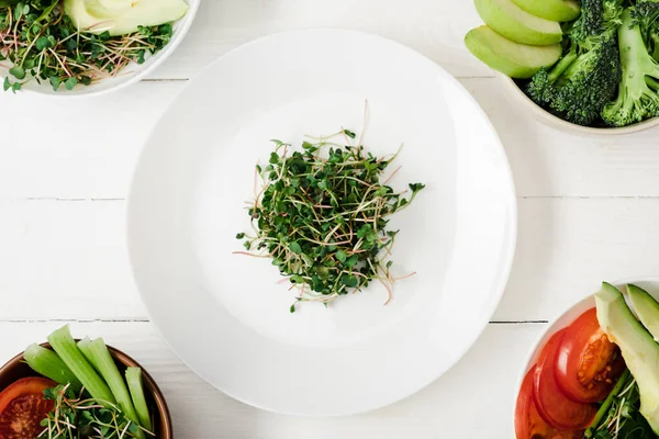 Vista superior de legumes frescos e frutas com microverde em tigelas na superfície de madeira branca — Fotografia de Stock