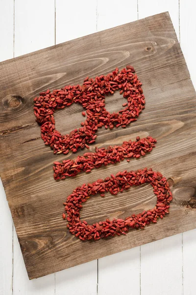 Draufsicht auf Wort Bio aus Goji-Beeren auf Schneidebrett auf weißer Holzoberfläche — Stockfoto