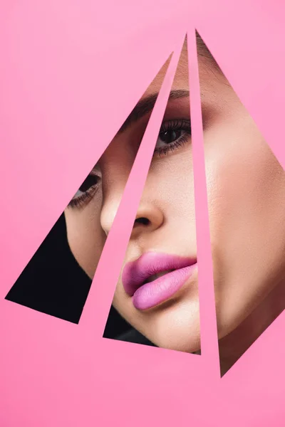 Mulher bonita com olhos fumegantes e lábios cor-de-rosa olhando através de buracos triangulares em papel em preto — Fotografia de Stock
