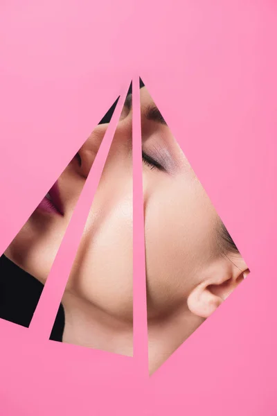 Female face with closed eyes across triangular holes in pink paper on black background — Stock Photo