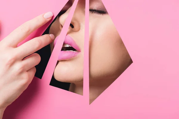 Woman with open mouth, closed eyes and pink lips across holes touching paper with hand on black background — Stock Photo