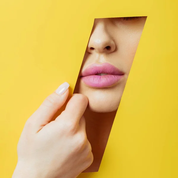 Ausgeschnittene Ansicht einer Frau mit rosa Lippen, die gelbes Papier berühren — Stockfoto