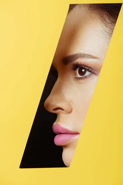 Female profile in quadrangular hole in yellow paper on black background — Stock Photo