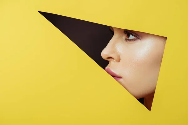 Female profile in triangular hole in yellow paper on black background — Stock Photo