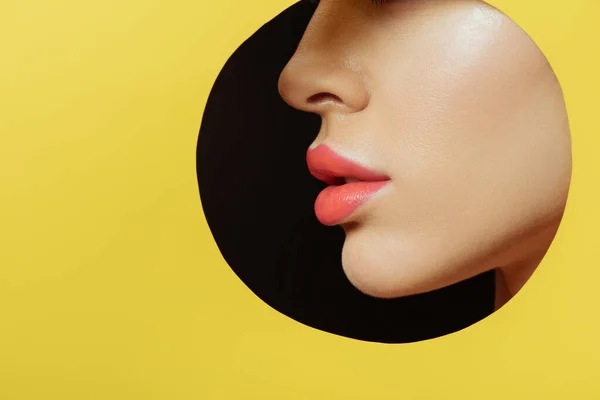 Cropped view of female profile in round hole in yellow paper on black background — Stock Photo