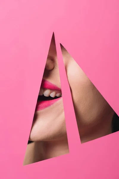 Cropped view of woman with pink lips smiling in triangular holes in paper — Stock Photo