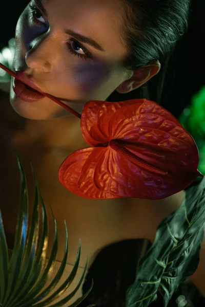 Селективный фокус женщины с красным антуром во рту рядом с зелеными листьями, изолированными на черном — стоковое фото