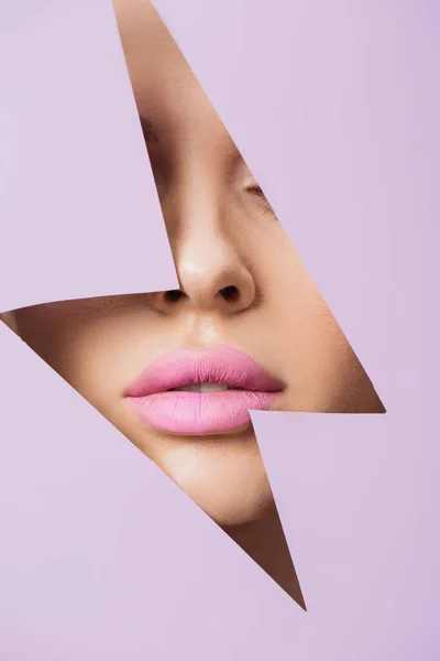 Cropped view of female face with pink lips in hole in violet paper — Stock Photo