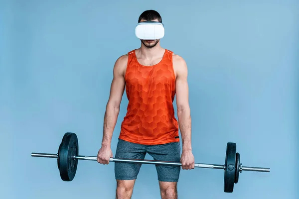 Desportista em realidade virtual headset exercício com barbell isolado em azul — Fotografia de Stock