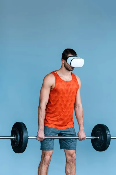 Desportista em realidade virtual headset trabalhando fora com barbell isolado em azul — Fotografia de Stock