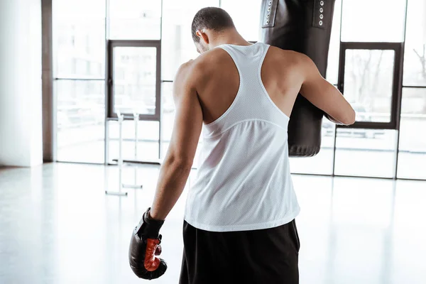Visão traseira do desportista em luva de boxe tocando saco de perfuração — Fotografia de Stock
