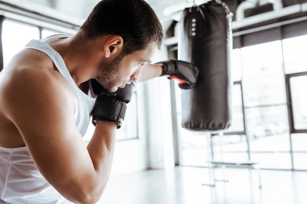 Foco seletivo do esportista atlético no treinamento de luvas de boxe com saco de perfuração — Fotografia de Stock