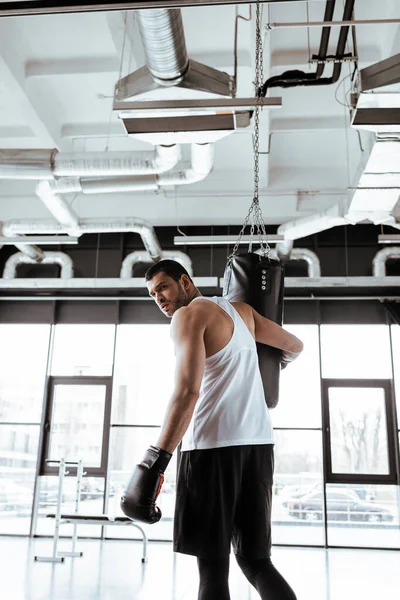 Schöner Sportler blickt in die Kamera in der Nähe von Boxsack — Stockfoto