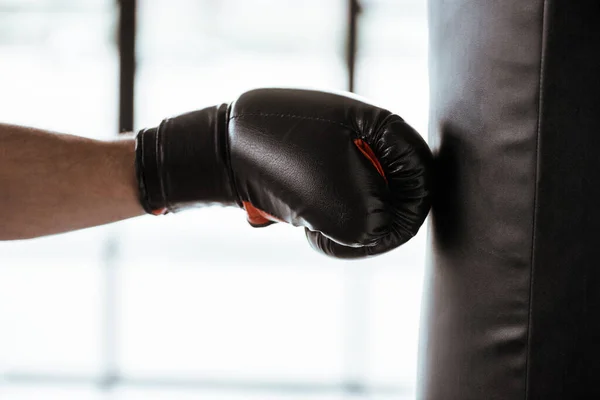 Vista recortada de deportista en entrenamiento de guante de boxeo con saco de boxeo - foto de stock