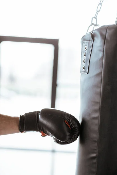 Cropped view of sportive man in boxing glove training with punching bag — Stock Photo