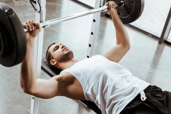 Foco seletivo de belo desportista exercitando com barbell no ginásio — Fotografia de Stock