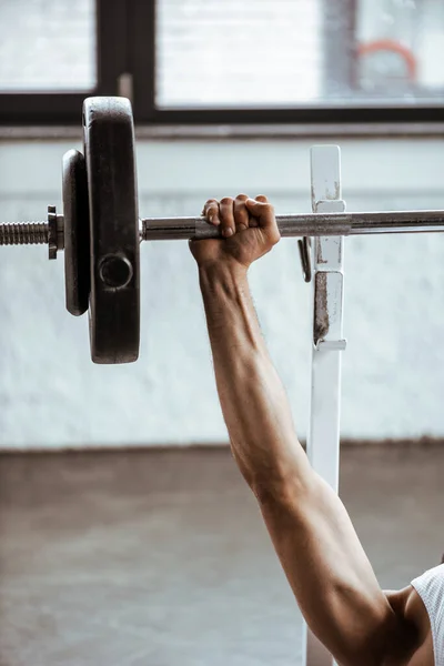 Cropped view of sportsman working out with barbell in gym — Stock Photo