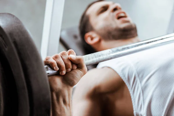 Selective focus of emotional man exercising with barbell — Stock Photo