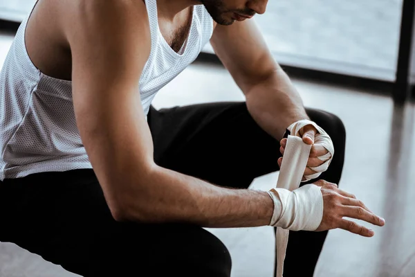Обрезанный вид спортсмена, завернувшего руку в спортивную повязку — стоковое фото