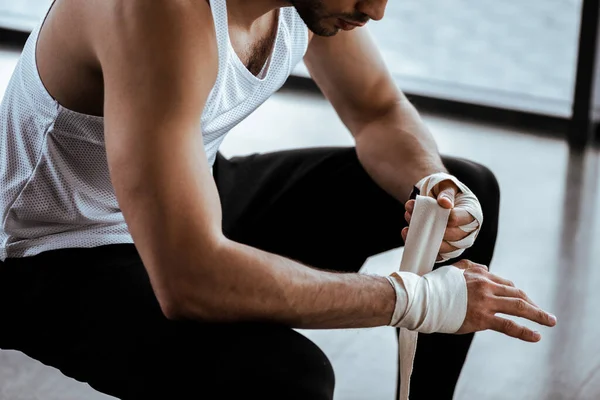 Vista ritagliata dell'uomo sportivo che avvolge la mano in benda sportiva — Foto stock