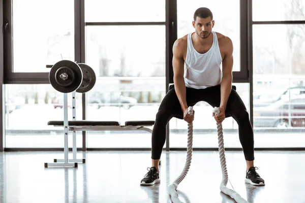 Bell'uomo sportivo che si allena con le corde da battaglia in palestra — Foto stock