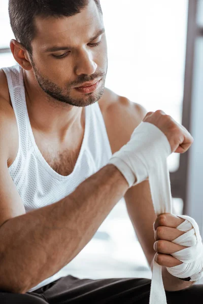 Selective focus of handsome sportsman wrapping hand in sports bandage — Stock Photo
