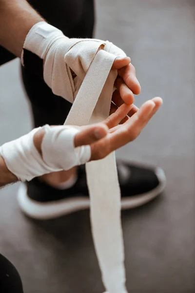 Vue recadrée de l'homme enveloppant la main dans un bandage de sport — Photo de stock