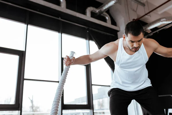 Uomo concentrato che si allena con corda da battaglia in palestra — Foto stock