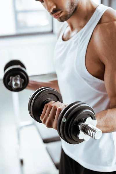 Cropped view of athletic sportsman exercising with dumbbells in gym — Stock Photo