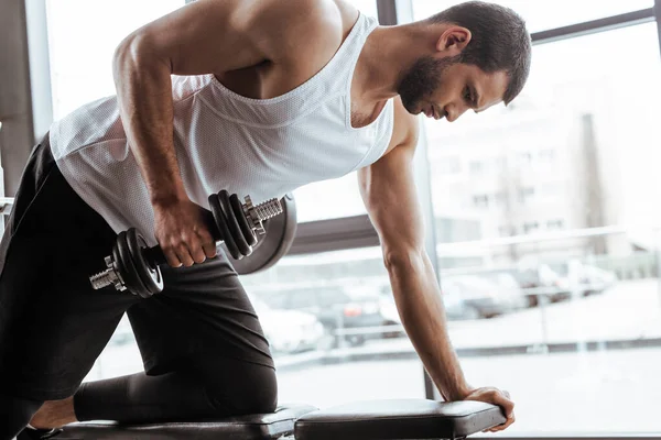 Athletic man exercising with dumbbell in gym — Stock Photo
