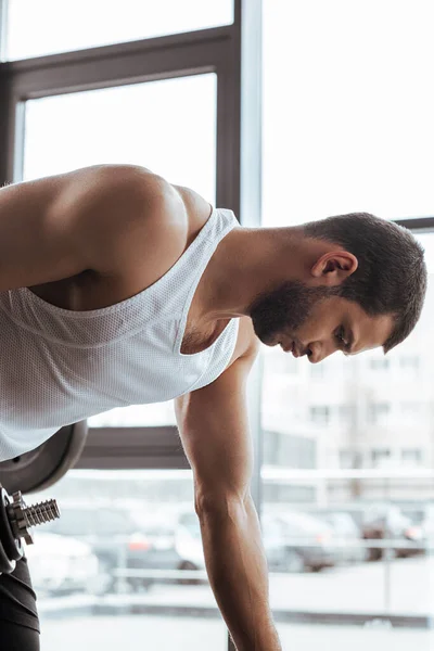 Vista lateral del deportista atlético haciendo ejercicio cerca de ventanas en el gimnasio - foto de stock