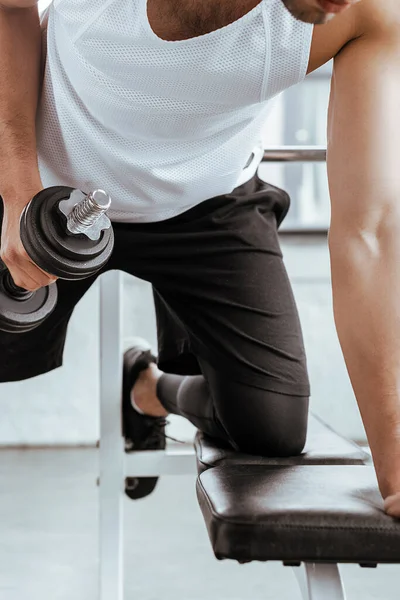 Vue recadrée de l'homme athlétique exercice avec haltère lourd dans la salle de gym — Photo de stock